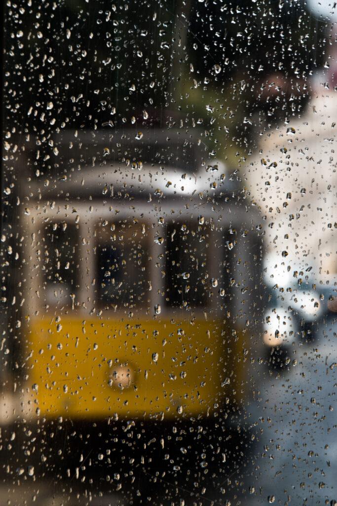 Atmospheric Yellow Tram Scene Through Rain-Drenched Glass Wallpaper