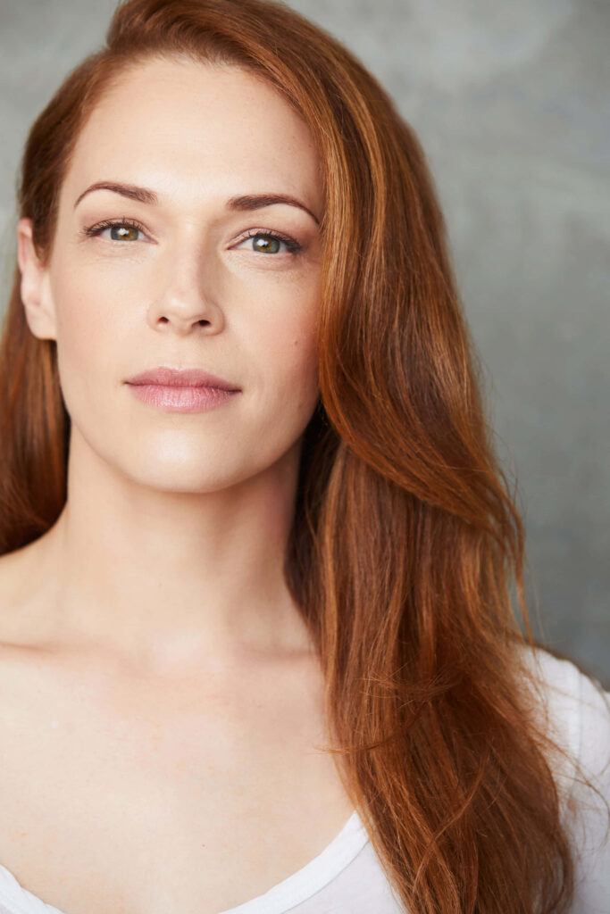 Auburn haired Amanda Righetti natural beauty portrait on soft minimalist wallpaper background