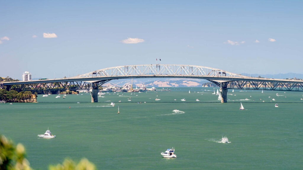 Auckland Harbour Bridge over turquoise water with boats in sunlit vibrant blue sky bay Wallpaper