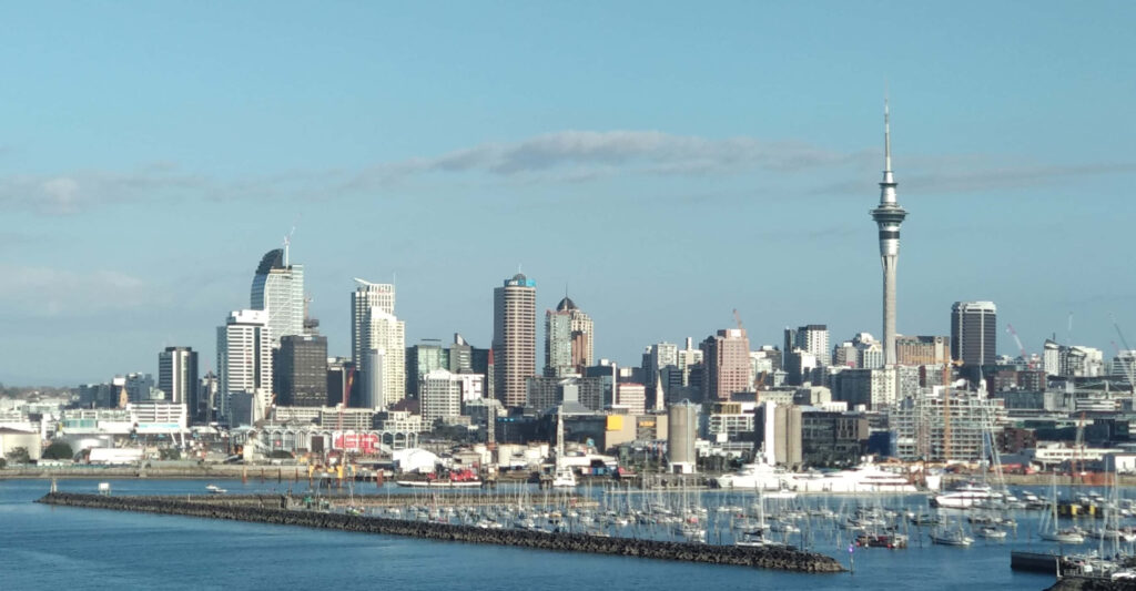 Auckland skyline at sunset with iconic skyscrapers Sky Tower and golden waterfront view wallpaper