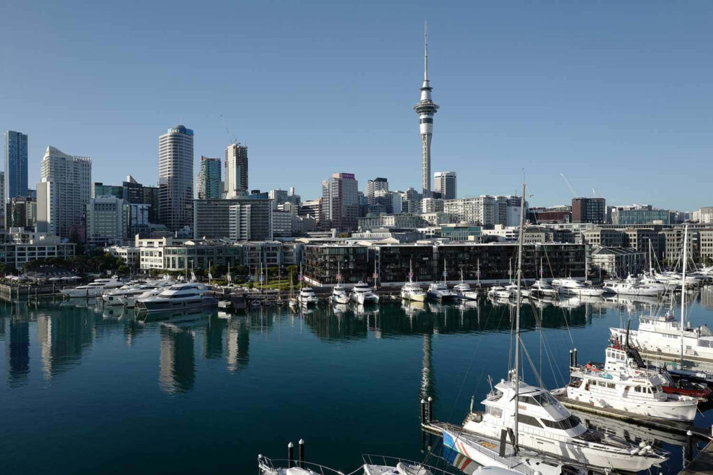 Auckland skyline with Sky Tower high-rises yachts calm water reflection clear sky wallpaper