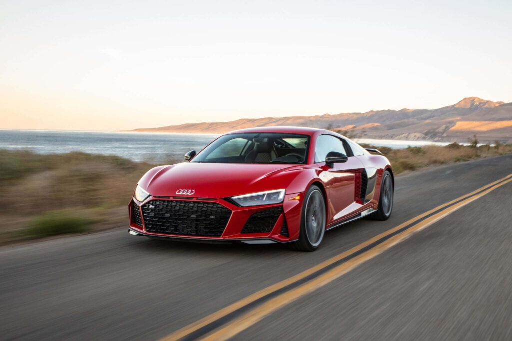 Red Audi R8 driving on coastal road with ocean views and clear skies summer wallpaper background
