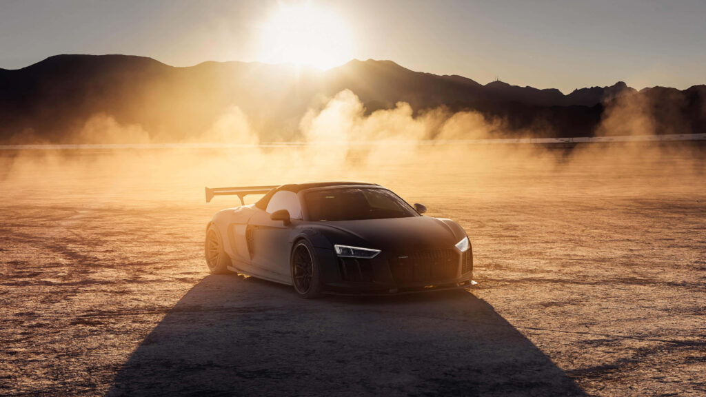 Audi R8 on sunlit mountain road with dramatic dust and glowing evening light wallpaper