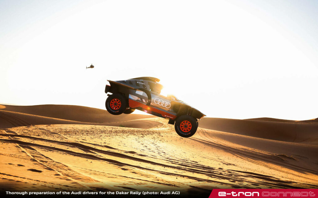 Audi rally car jumping over golden sand dunes off-road adventure under bright sunny sky wallpaper