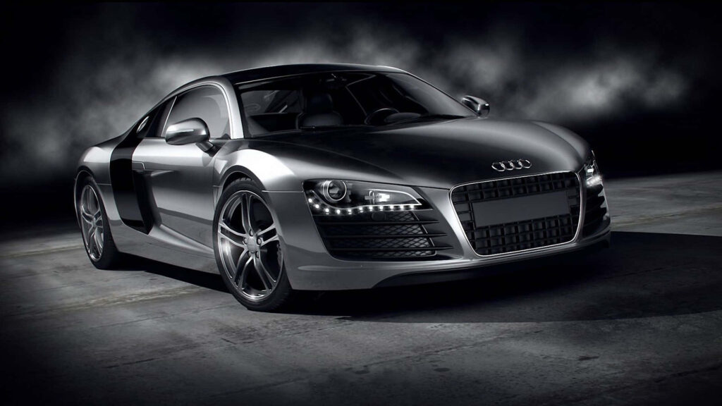 Audi sports car glowing under city lights at night showcasing sleek modern design and power Wallpaper