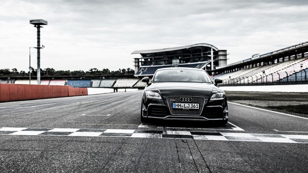 Audi TT Racecar Black Edition head-on at racetrack sleek design grandstand cloudy sky wallpaper