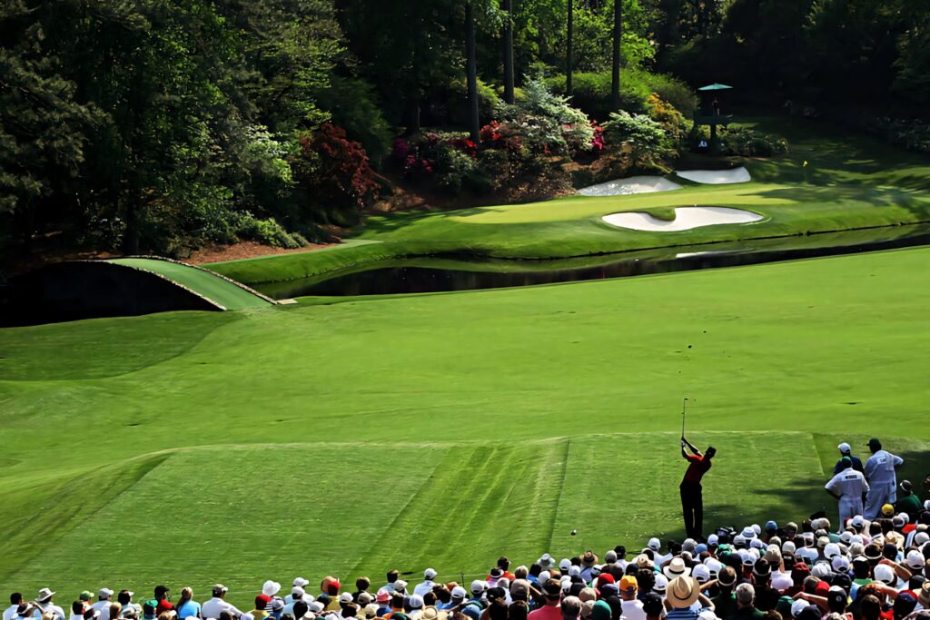 Golfers tee-off at iconic Augusta National Golf Course with vibrant azaleas and lush greenery Wallpaper