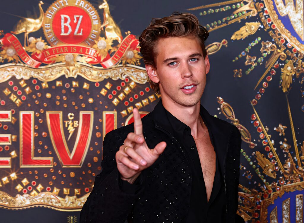 Austin Butler as Elvis Presley with bold gold red patterns backdrop stylish cinematic glamour Wallpaper