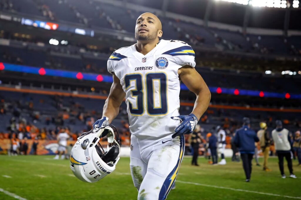 Austin Ekeler in Chargers uniform holding helmet looking determined on football field after game Wallpaper
