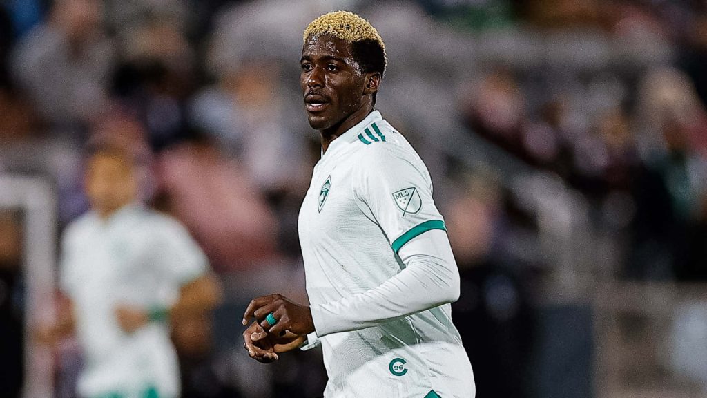Austin FC striker Gyasi Zardes in white kit with blonde hair in intense MLS match vs Charlotte FC wallpaper