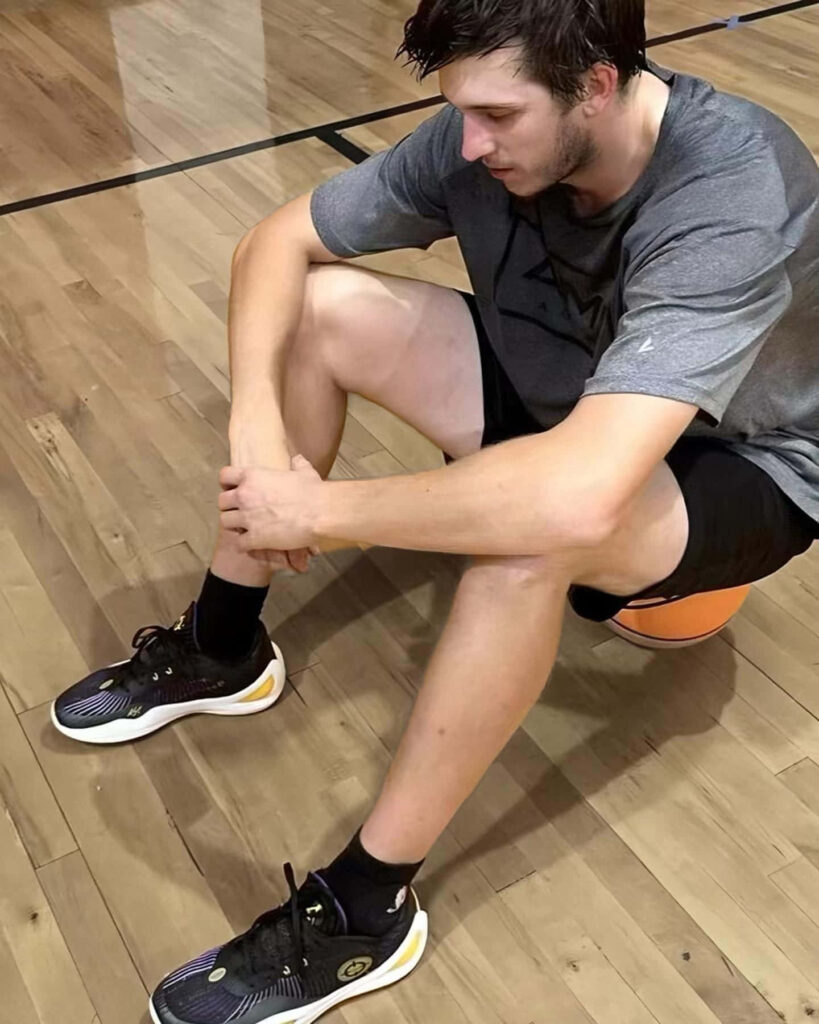 Austin Reaves resting on basketball court in training gear and shoes after intense practice session Wallpaper