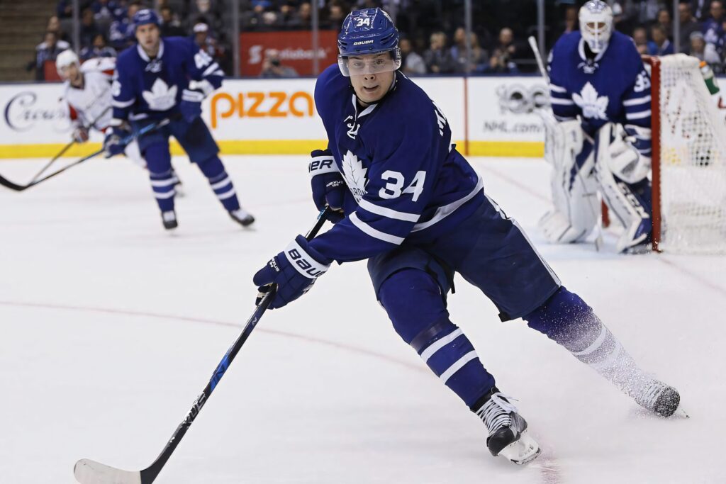 Auston Matthews wearing Toronto Maple Leafs jersey playing intense professional hockey game on ice Wallpaper