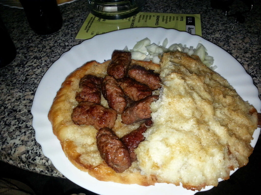 Authentic Balkan ćevapi grilled sausages on fluffy flatbread with chopped onions traditional food Wallpaper