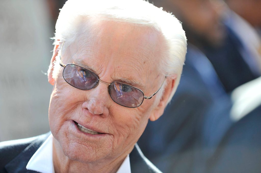 Candid close-up portrait of country music legend George Jones in dark suit and glasses Wallpaper