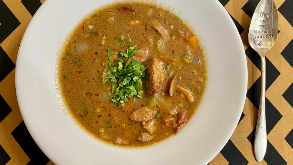 Appetizing Gumbo Bowl with Fresh Herbs and Engraved Spoon Wallpaper