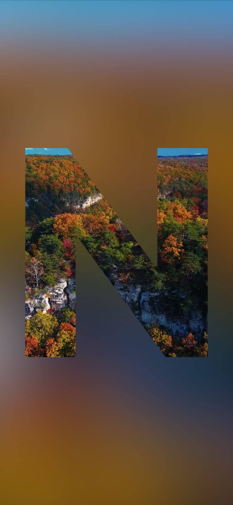 Artistic autumn wallpaper with letter N window showing vibrant fall forest and rocky cliffs
