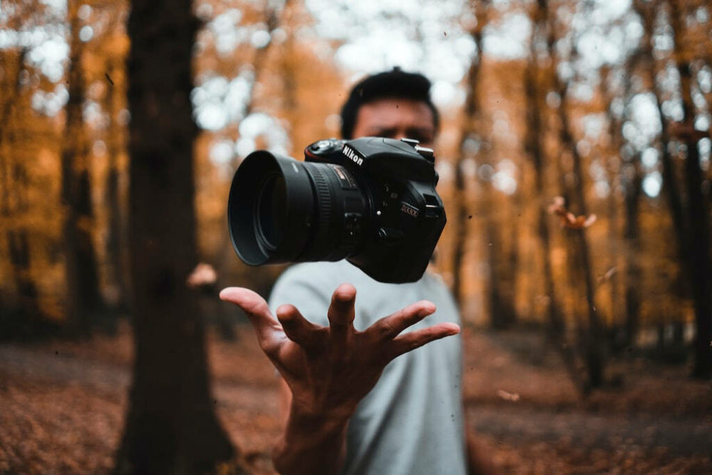 Capturing Autumn's Beauty: Skilled Cameraman Holds DSLR Canon amidst Vibrant Forest Setting Wallpaper