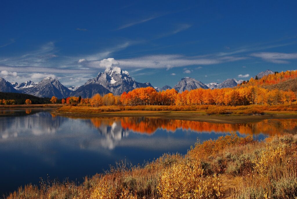 Autumn landscape wallpaper with clear lake reflecting snow-capped mountains and vibrant trees