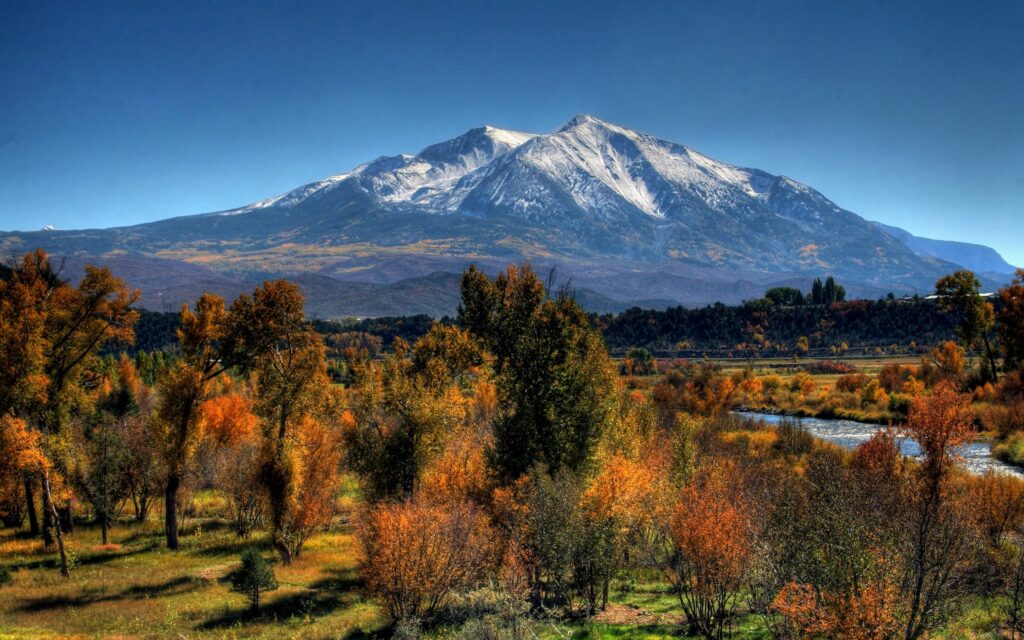 Autumn landscape with snow-capped mountains vibrant orange and gold trees and winding river wallpaper