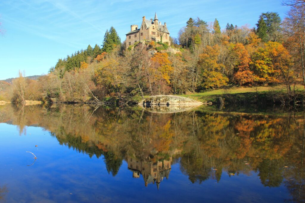 Fairytale castle above Loire Valley autumn trees reflected in calm lake serene landscape wallpaper