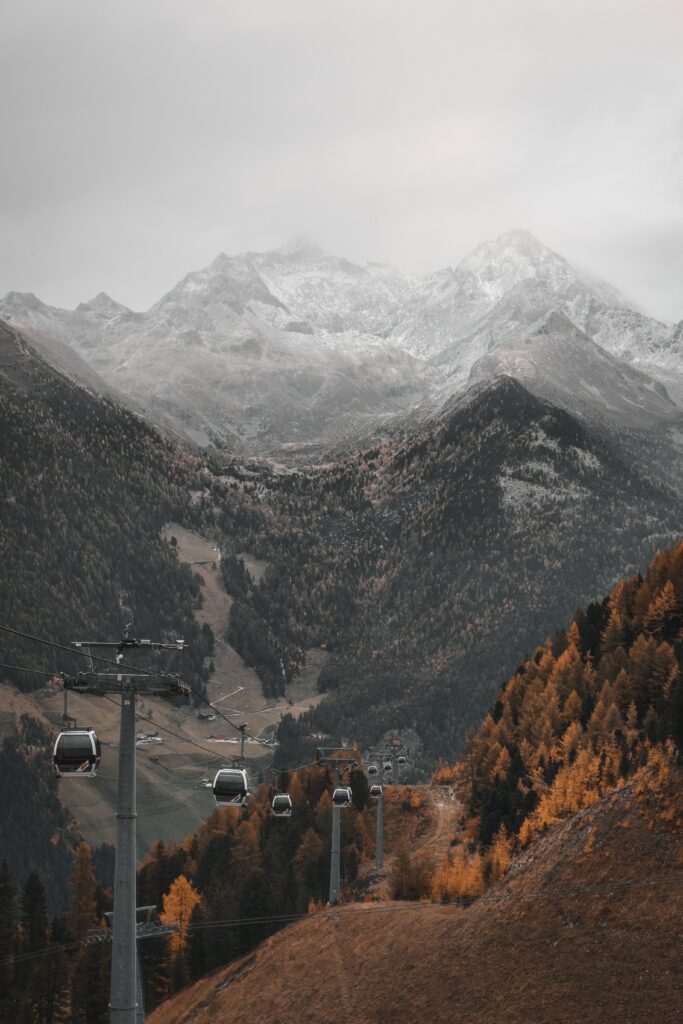 Cableway lift over autumn forest with mountain peaks under moody overcast sky wallpaper