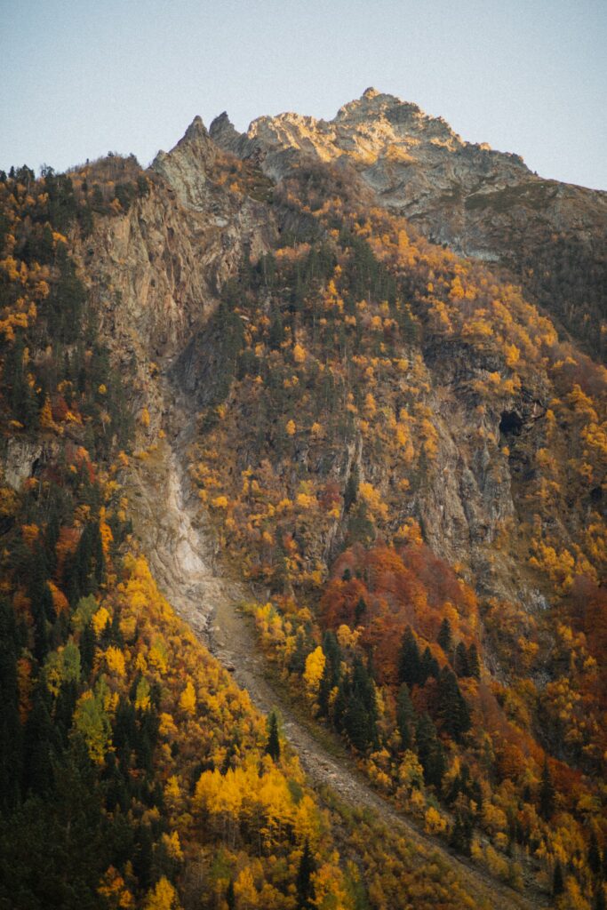 Autumn mountain peak with vibrant yellow orange red foliage and rugged rocky forest landscape wallpaper