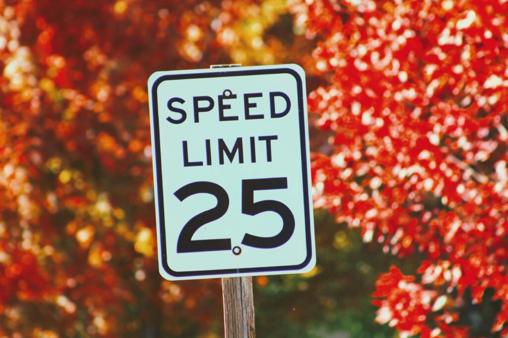 Autumn speed limit 25 sign with vibrant red orange foliage seasonal contrast background wallpaper