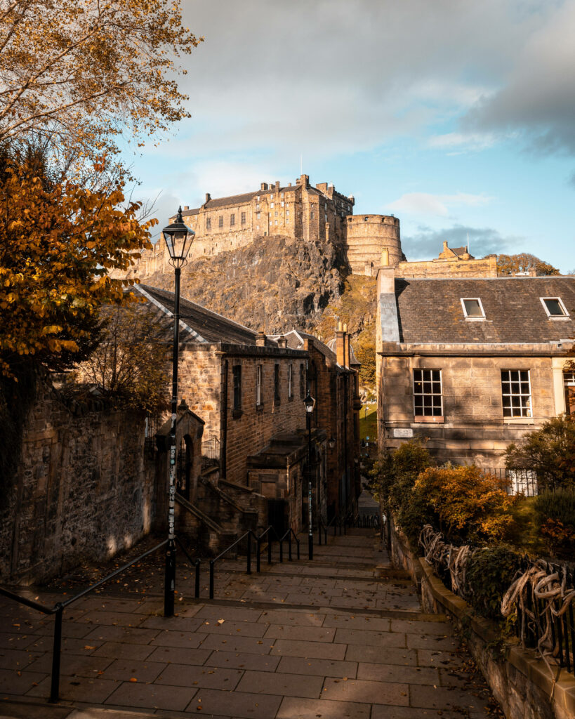 Autumn street in Edinburgh with golden leaves historic stone buildings and Edinburgh Castle view Wallpaper