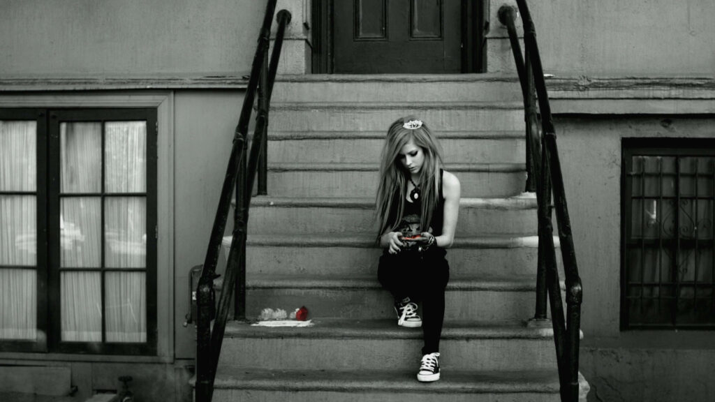 Avril Lavigne punk style sitting alone on outdoor steps with reflective moody teenage vibe wallpaper