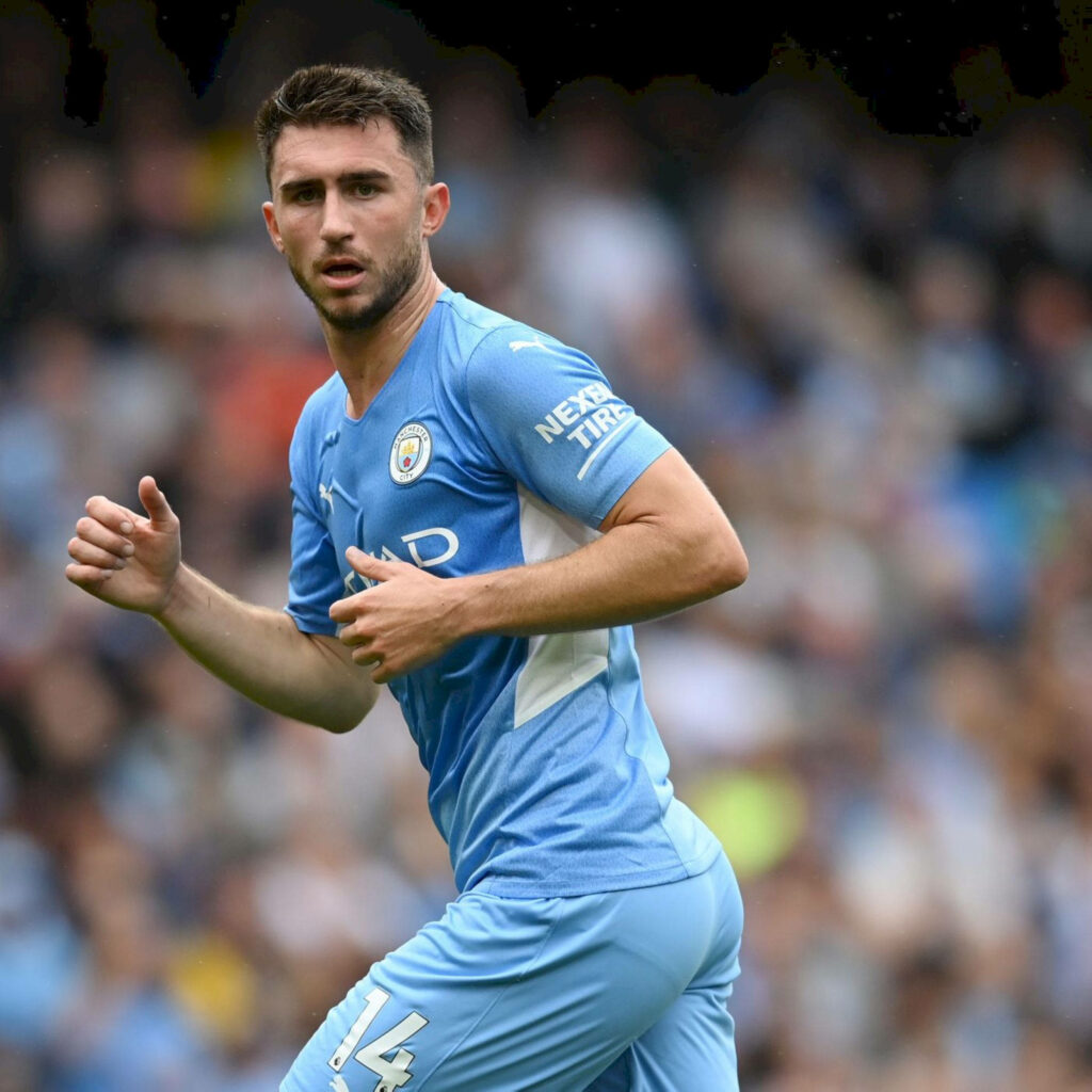 Aymeric Laporte sprinting in Manchester City kit showing focus determination during match Wallpaper