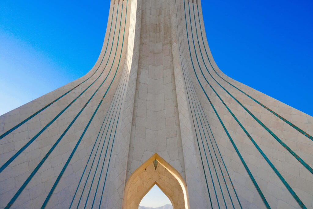 Tall side view of Azadi Tower Tehran Iran with elegant architecture against clear blue sky wallpaper