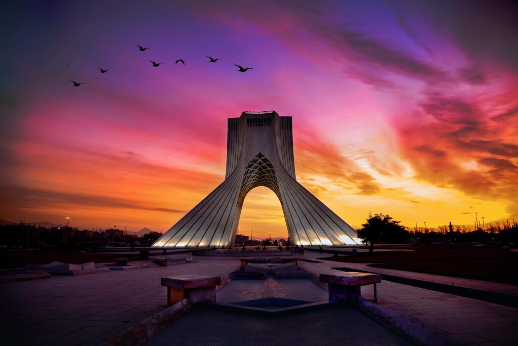 Azadi Tower Tehran at sunset with birds flying creating a serene vibrant wallpaper background