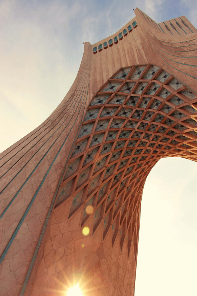 Azadi Tower Tehran sunset wallpaper with sun shining through geometric arches and soft sky