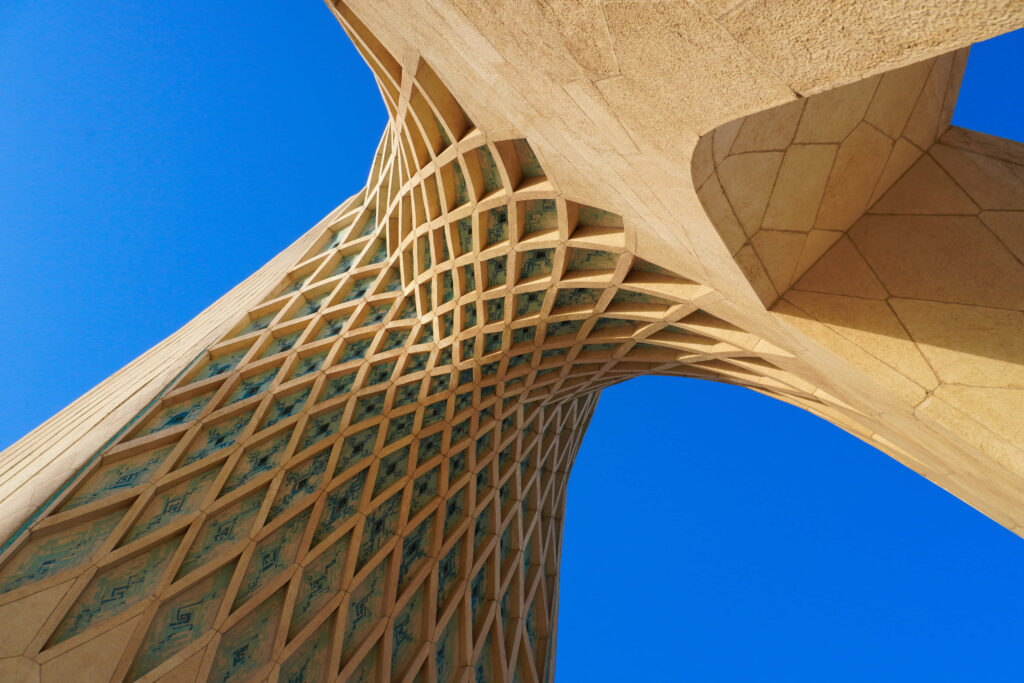Underside view of Azadi Tower lattice architecture in Tehran against vivid blue sky wallpaper