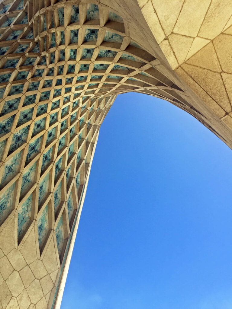 Upward view of Azadi Tower Tehran with intricate geometric patterns against clear blue sky wallpaper