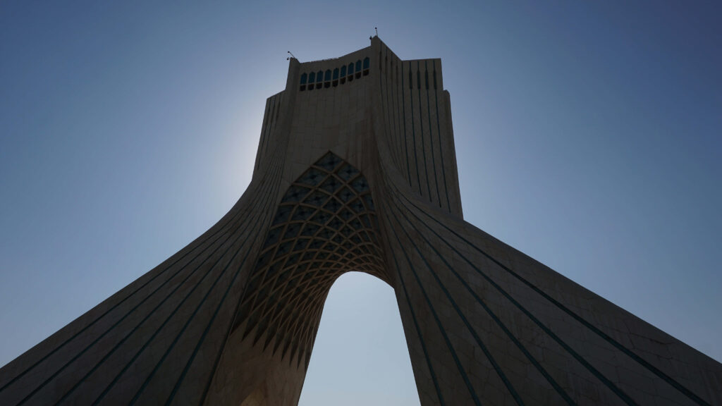 Azadi Tower Tehran silhouette with sun highlighting unique architecture wallpaper background