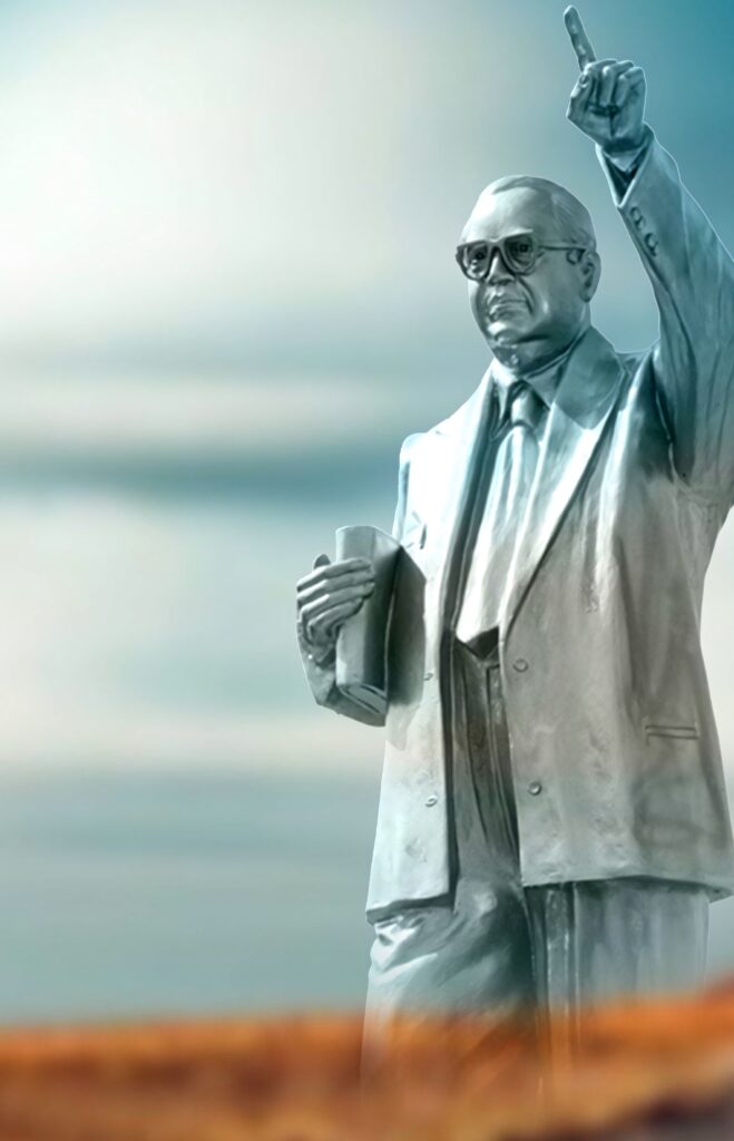 Statue of B R Ambedkar in formal suit holding book and raising finger with soft blue background Wallpaper