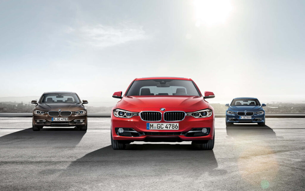 BMW cars in red blue and brown parked with city skyline showcasing sleek modern design Wallpaper