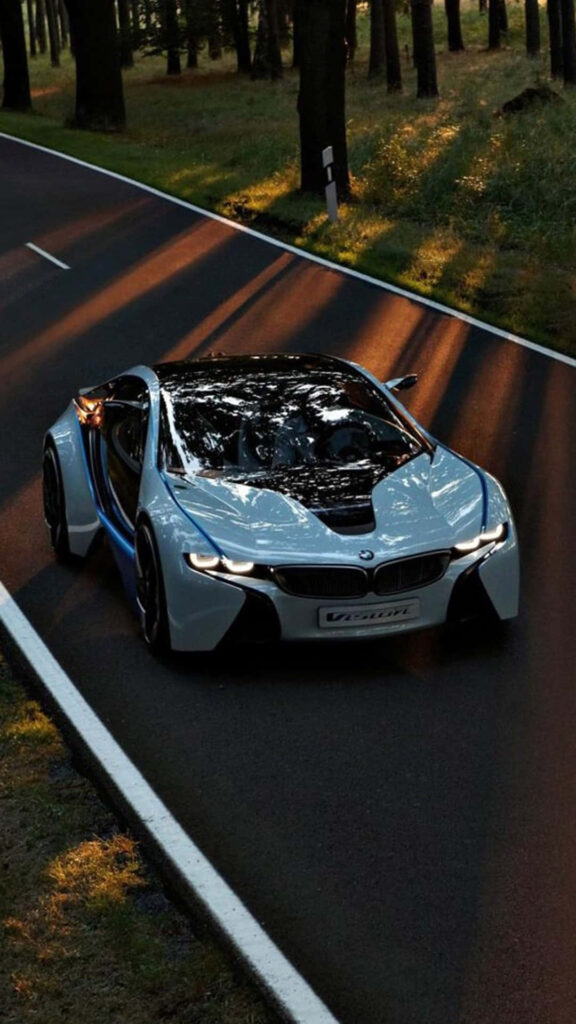 BMW concept car driving on forest road bathed in golden sunlight showcasing innovation and speed Wallpaper