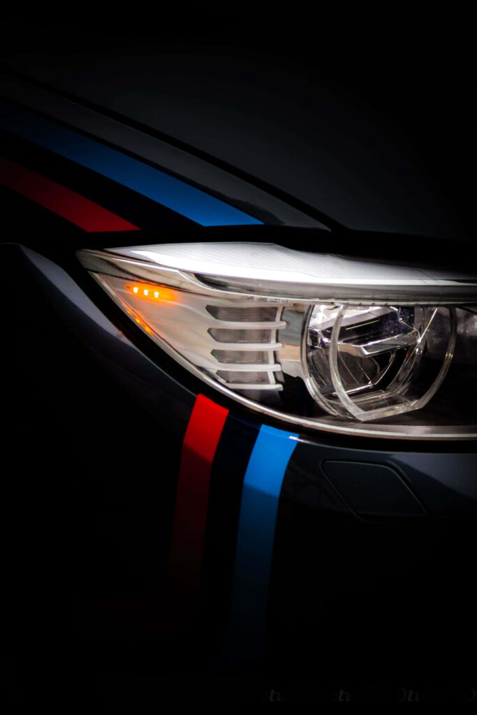 Close up BMW headlight with sharp LED details and blue red M stripes sleek modern design Wallpaper