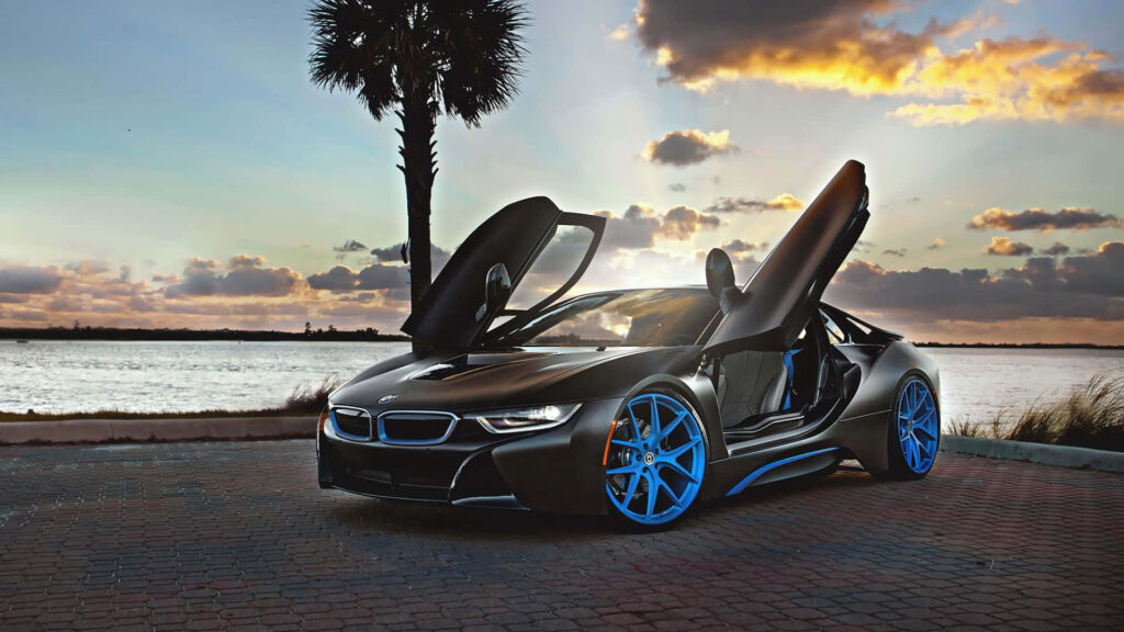BMW i8 Convertible with scissor doors open by waterfront during vibrant sunset wallpaper background