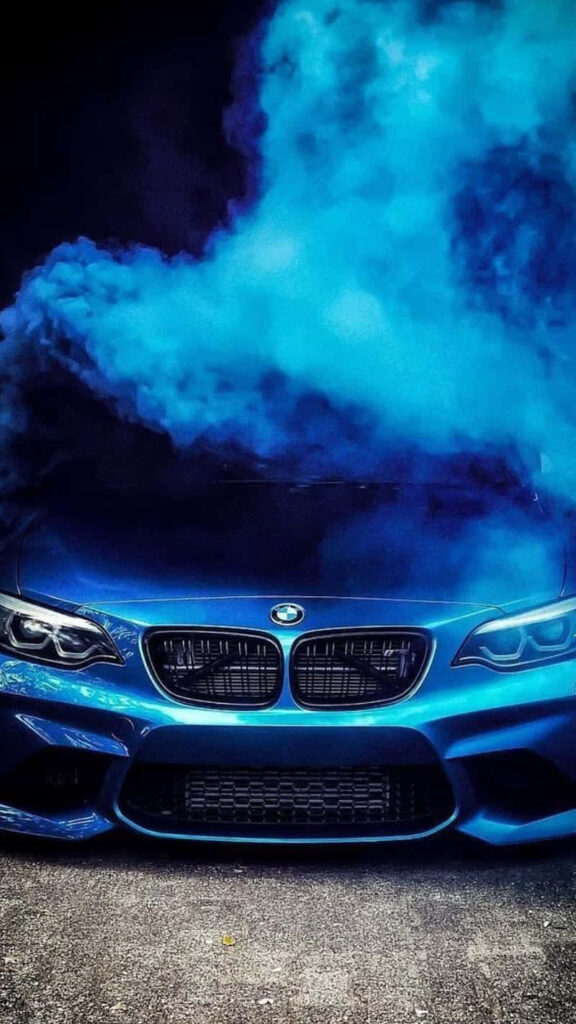 BMW M4 with aggressive front and vibrant blue smoke on wallpaper background dynamic presence
