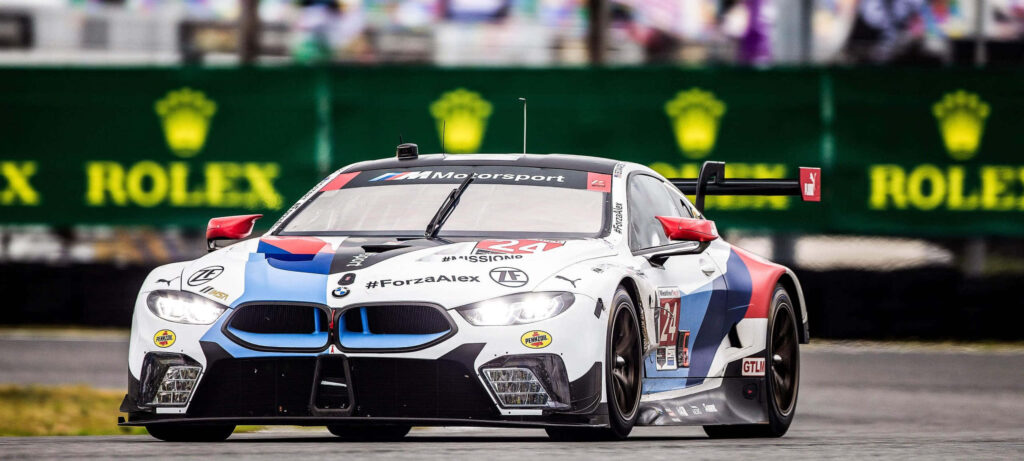 BMW M8 sports car speeding on race track with bold design and racing livery in 4K detail wallpaper