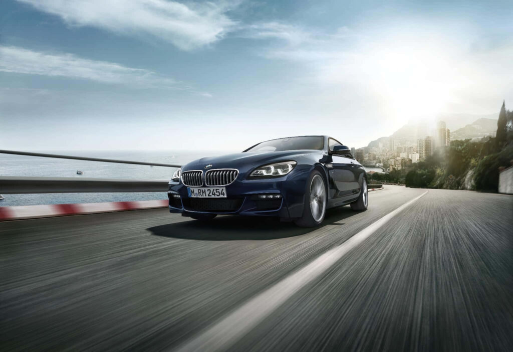Sleek BMW car speeding on coastal highway showcasing high performance and dynamic energy wallpaper
