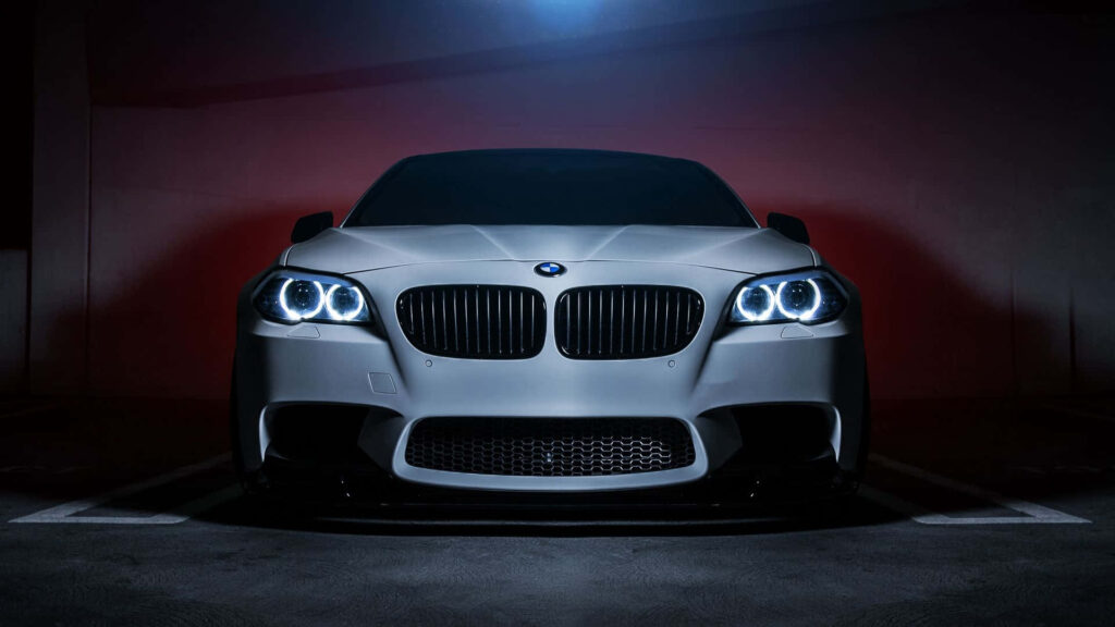 Front view of BMW X5 M3 showcasing sleek lines and LED headlights in a dark setting wallpaper