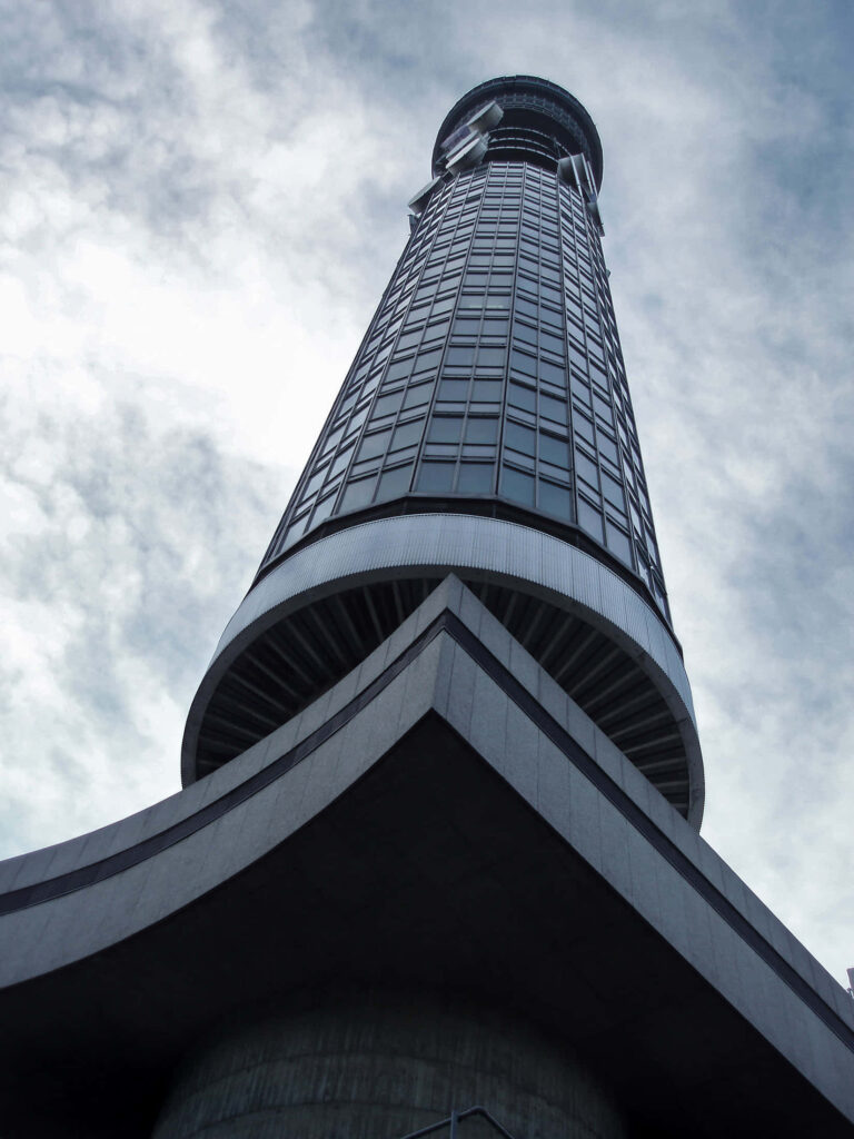 Upward view of BT Tower with sleek glass windows against cloudy sky urban architecture wallpaper