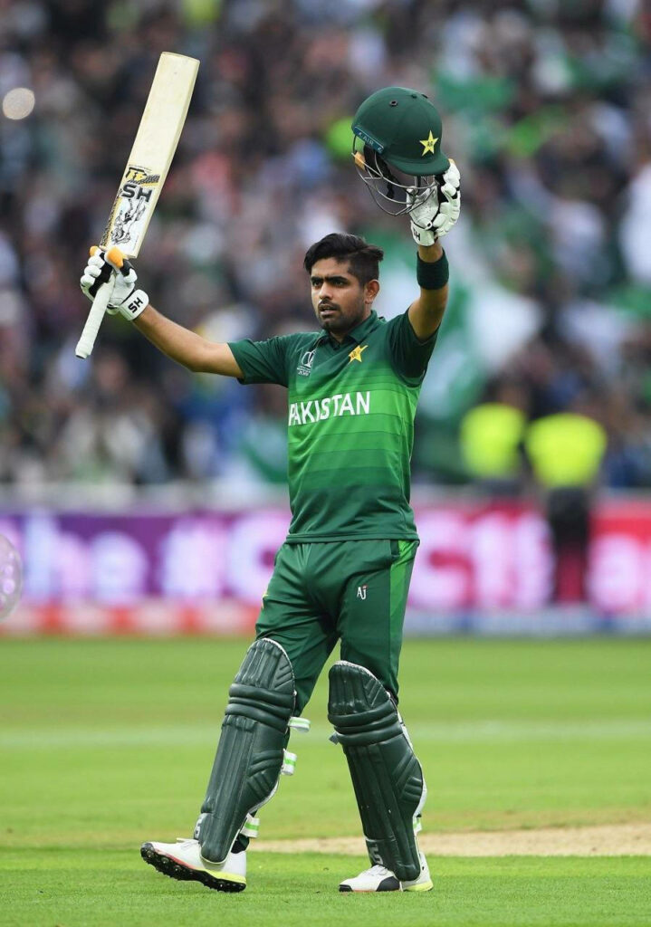 Babar Azam celebrates cricket milestone on field raising bat and helmet in front of crowd wallpaper