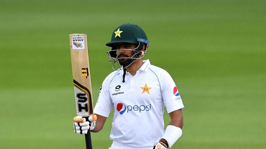 Babar Azam Pakistan cricket captain in white Test uniform holding bat on field wallpaper background