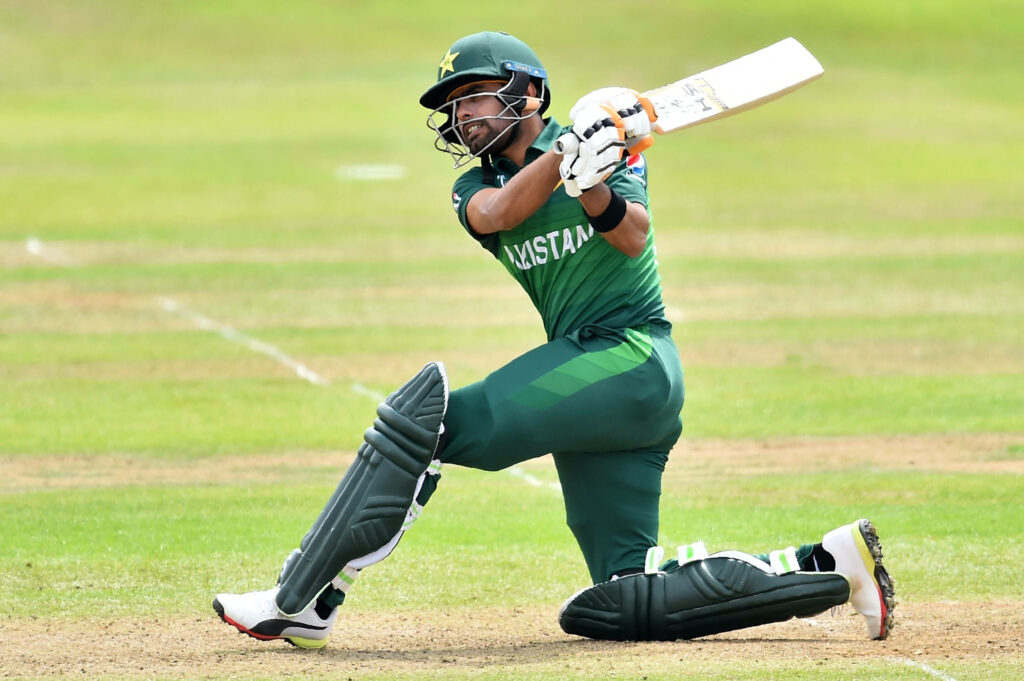 Babar Azam batting on one knee in Pakistan cricket kit showing skill and focus on pitch Wallpaper