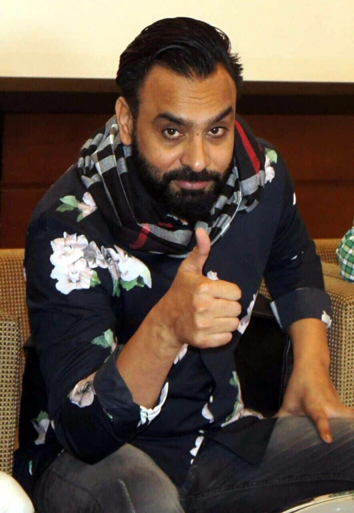 Babbu Maan smiling confidently thumbs up floral shirt patterned scarf wallpaper background